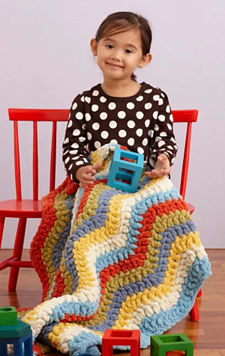 girl sitting in chair with crochet blanket in her lap
