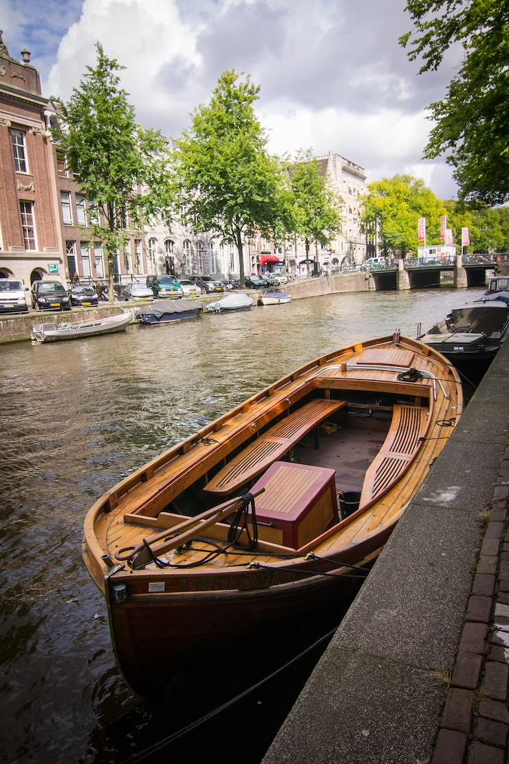 Wooden boat by the canal surrounded by houses captured in Amsterdam