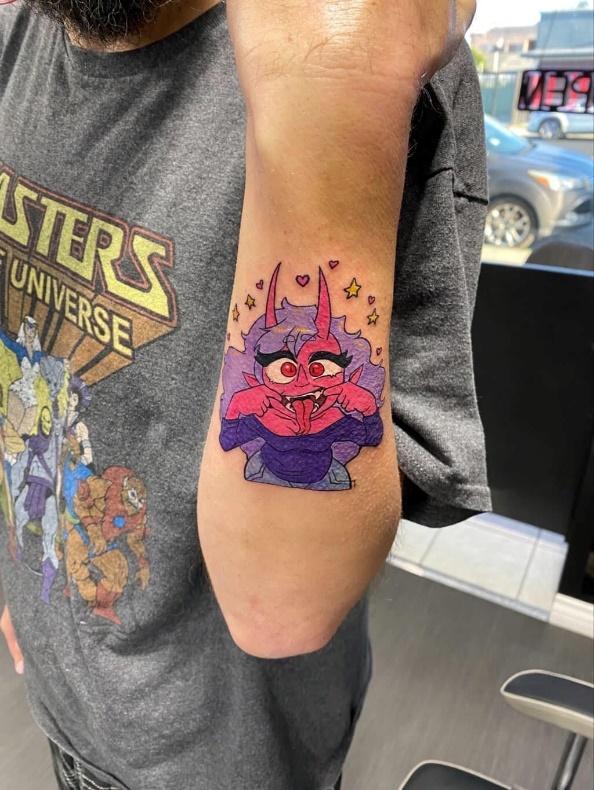A man's forearm with a tattoo of a pink and purple fantasy character
