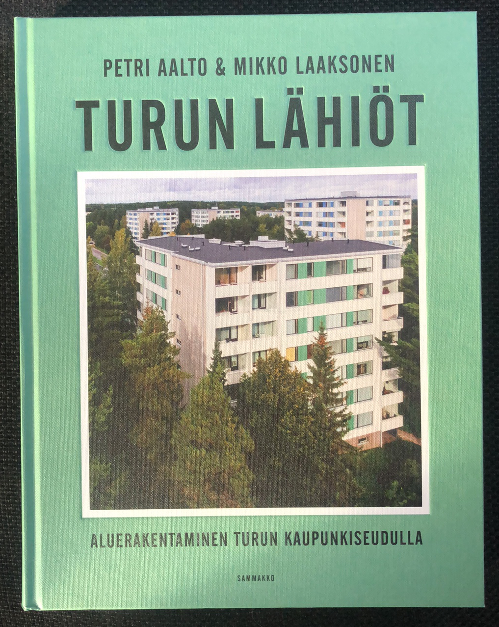 Turun lähiöt -kirjan kansikuva, jossa on kerrostaloja metsän keskellä.