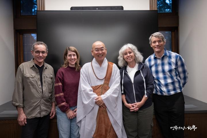 A group of people standing in front of a black wall  Description automatically generated