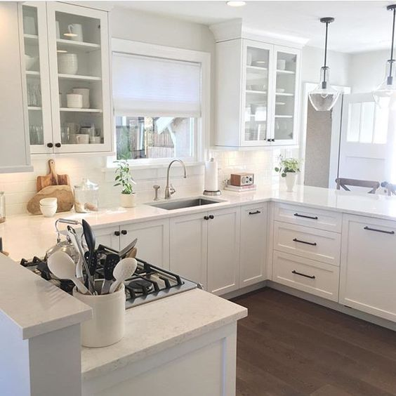 u-shaped kitchen with white shaker cabinets and matte black hardware. the layout divides a large space into a main kitchen work area and sep