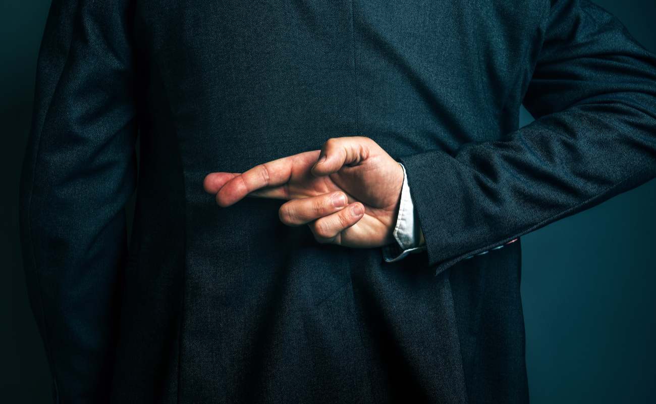 Hombre de negocios con traje negro cruzando los dedos detrás de la espalda