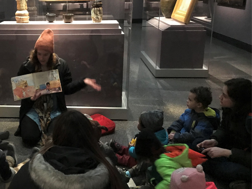 A teacher reads a book to a group of toddlers in the Freer Sackler 