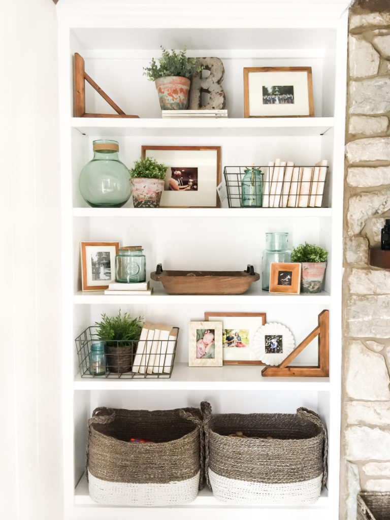 A white bookshelf that features lots of wooden and brown toned decor. 