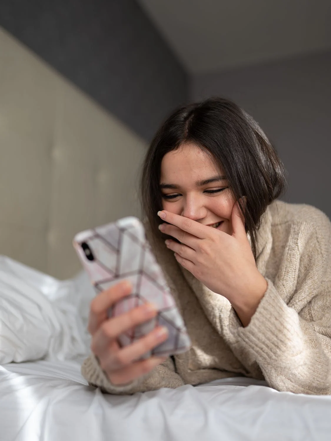 A Woman Smiling While Looking At Her Phone 