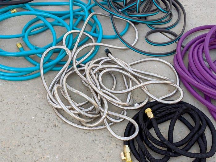 garden hoses of various materials and colors coiled on the ground to demonstrate what else we tested for the best gardening hose 2021