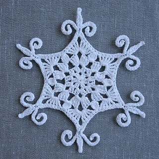 white crochet snowflake on fabric background
