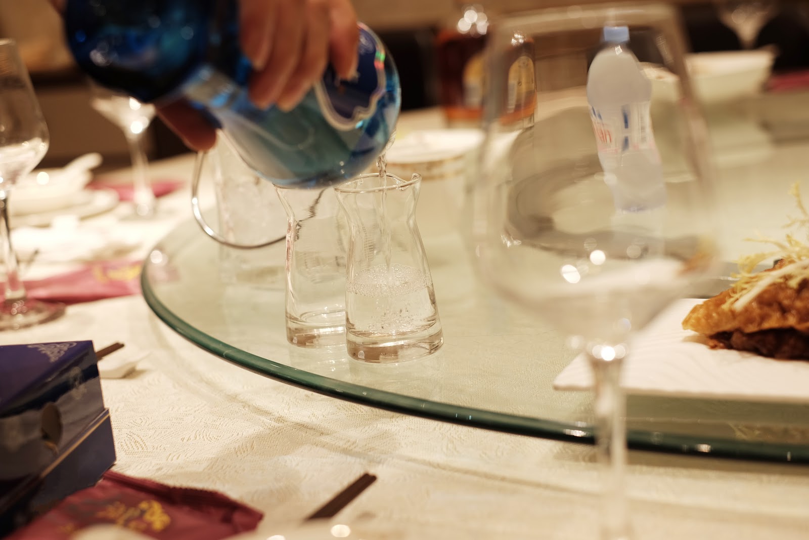 A Chinese dining table with strong spirit being poured into small glasses.