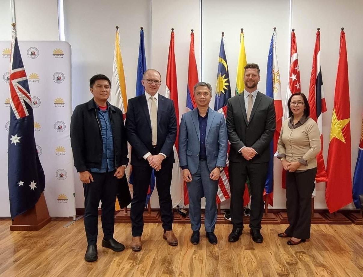 A group of people posing for a photo in front of flagsDescription automatically generated
