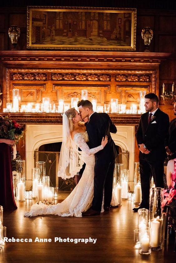 photo of bride and groom kissing in front of candelit mantle