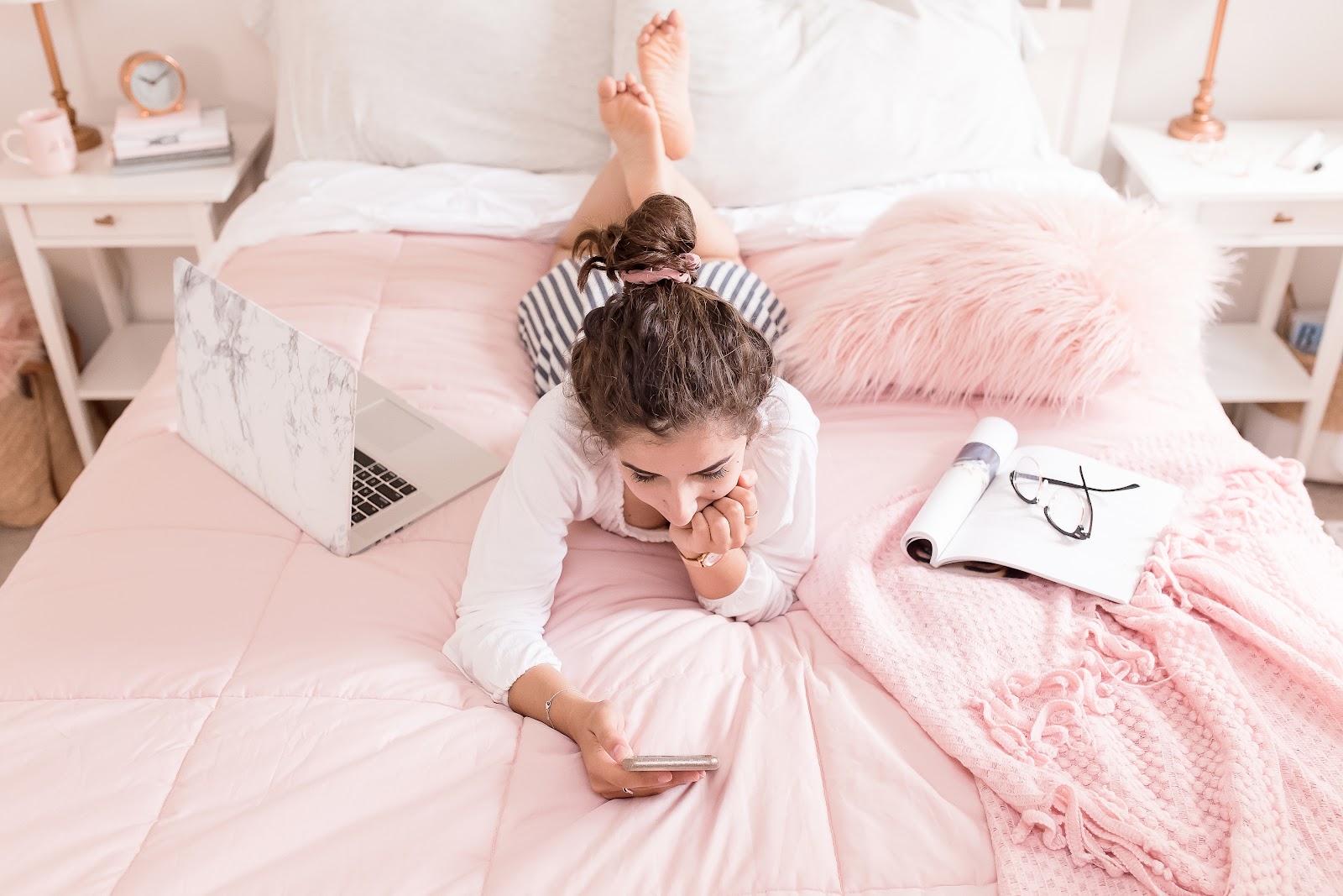 Girl lying on bed with phone, notebook, laptop, remote work, virtual work