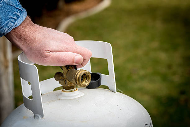 Man closes a knob on a propane tank stock photo
