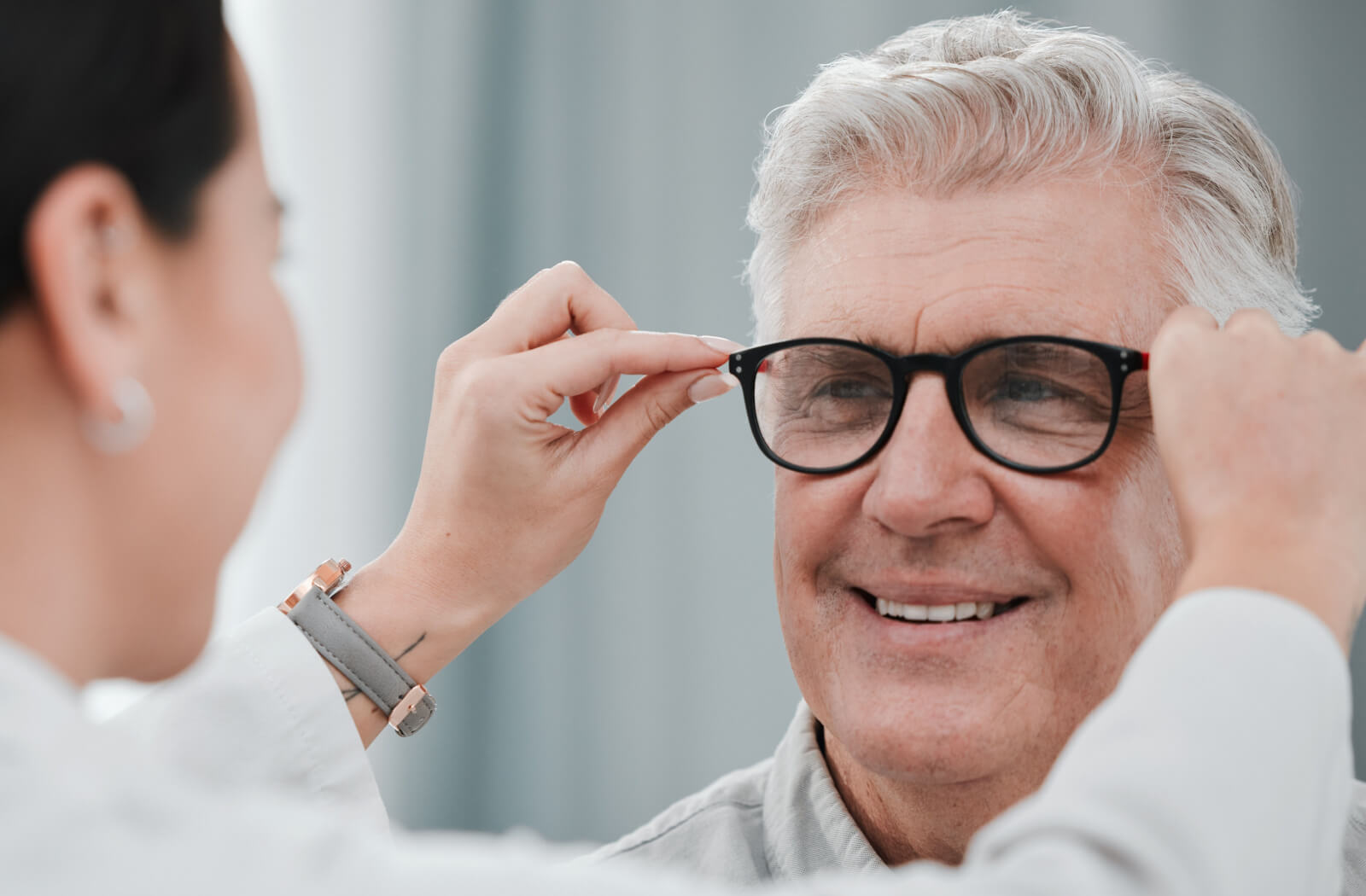 A senior man being fitted with prescription glasses by a female optometrist.