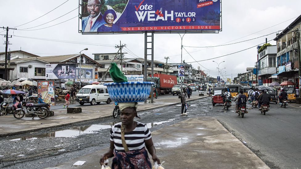 A woman walks past a campaign billboard for the President of Liberia George Weah in Monrovia - 4 October 2023