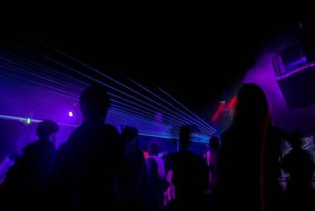 ナイトクラブの店内の写真。暗闇に紫色に光るライトが印象的。