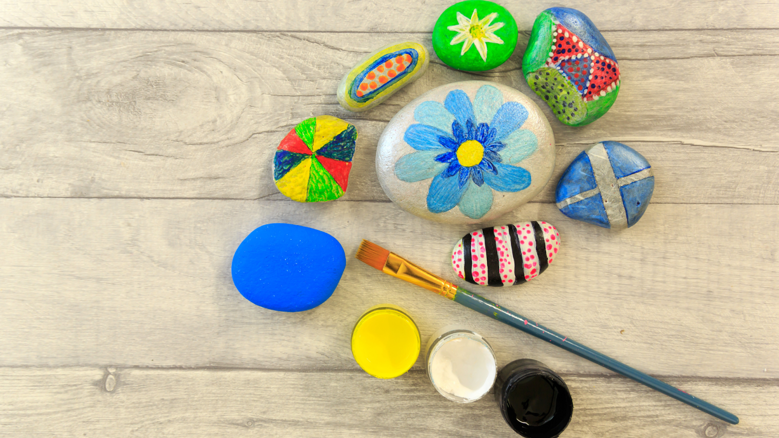 group of painted rocks with a paintbrush and paints next to them