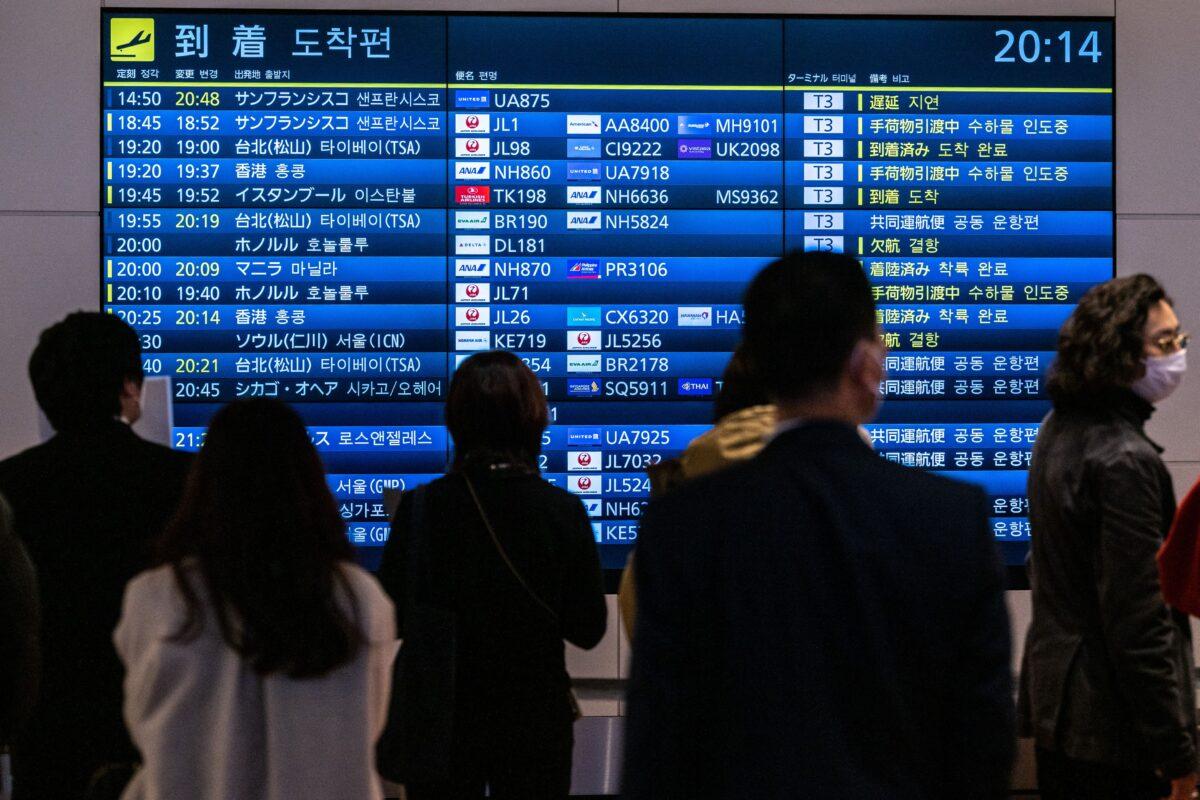 Mọi người theo dõi các chuyến bay quốc tế đến tại phi trường quốc tế Haneda của Tokyo, hôm 28/12/2022. (Ảnh: Philip Fong/AFP qua Getty Images)
