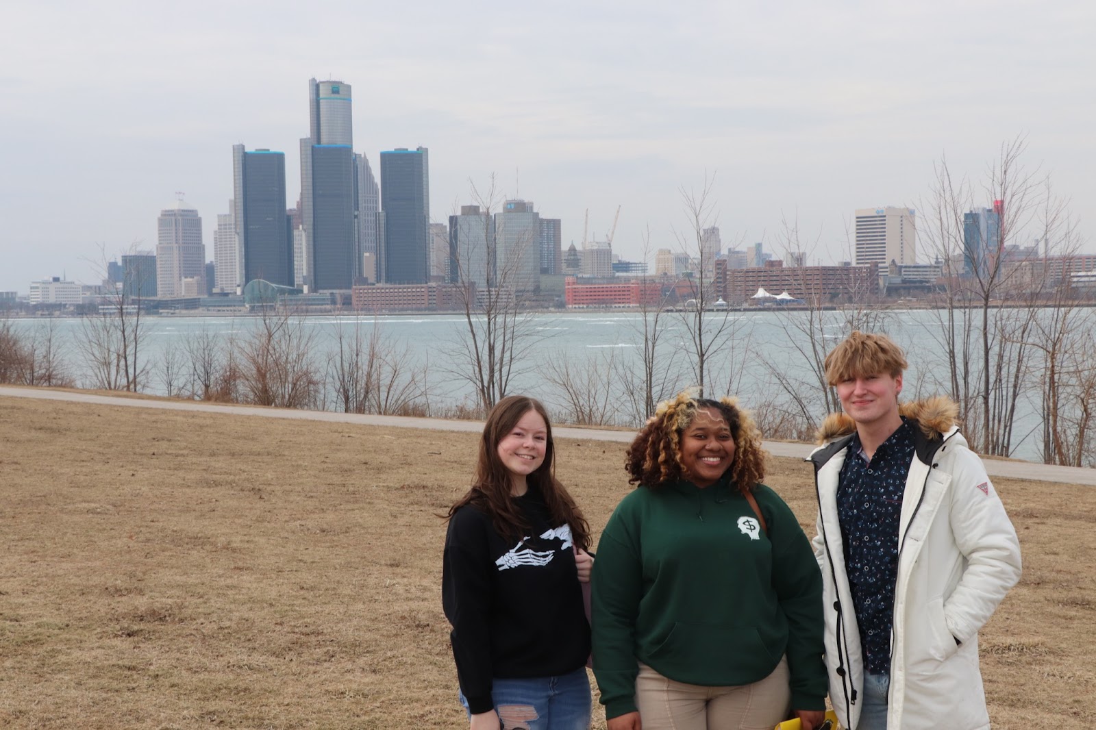 Students Nicole Greenen, MacKenzie Thompson, and Zackary Weber in Windsor, with the Detroit skyline behind them