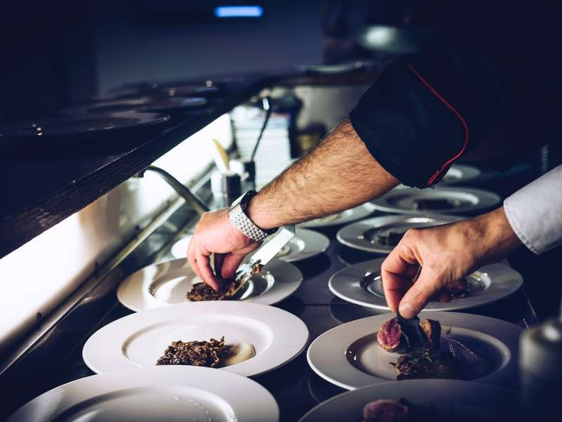 A personal chef putting food on a plate. 