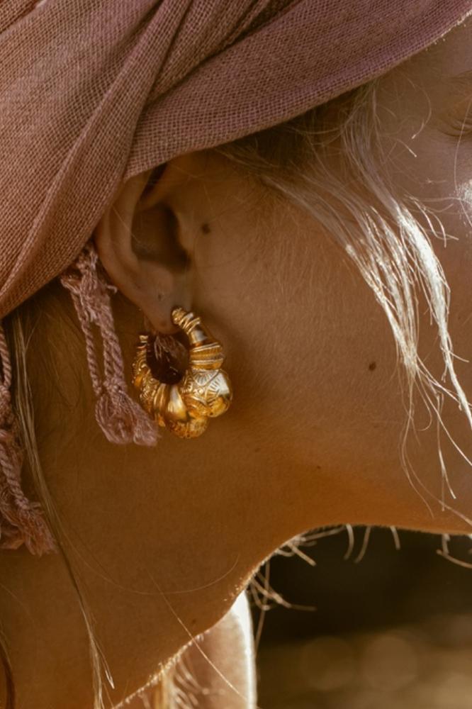 Close-up of a person wearing a hat and earring

Description automatically generated