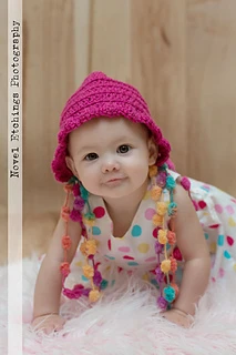 baby wearing pink bonnet on fur rug