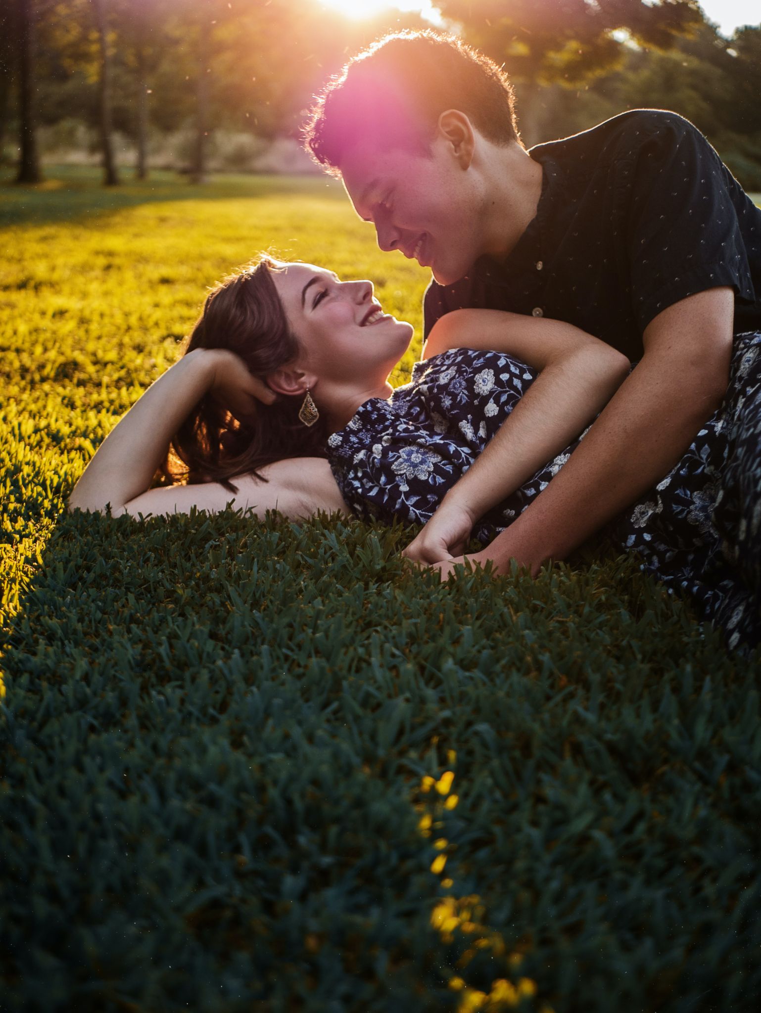 A picture of a woman lying on some grass, with a man lying next to her, looking at her lovingly, representing the phrase "I'm mad about you."