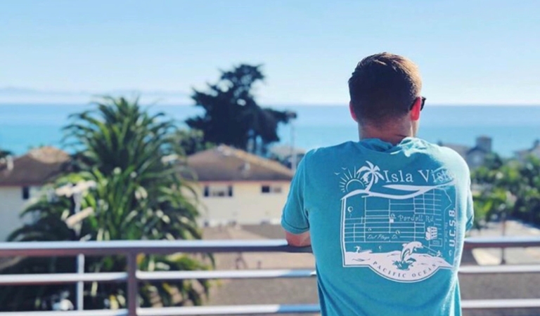 A man looking out from a balcony at Isla Vista and the ocean in the distance.