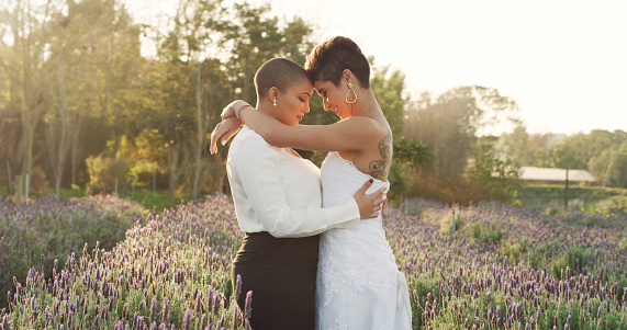 two lesbian women on their wedding day, standing in the middle of a lavender garden and posing while smiling and touching forehead. If you are struggling with relationship anxiety and OCD, our CBT therapist can help. Call today for Woodland Hills, CA 91364
