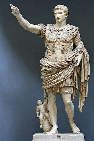 Standing statue of Augustus Caesar in Roman armor with upraised arm. There is for some reason a small child off to his side.
