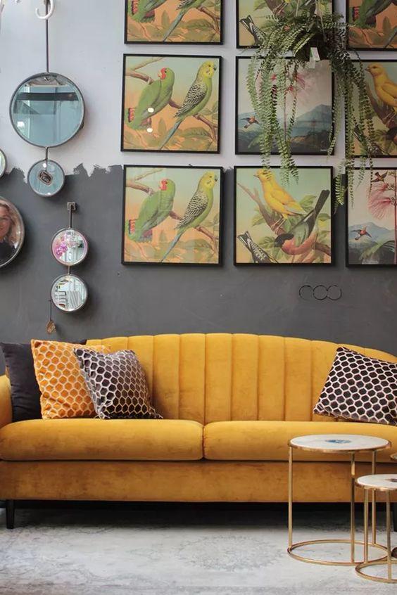 Sala com sofá amarelo, parede cinza e quadros decorativos em tons amarelo e cinza.