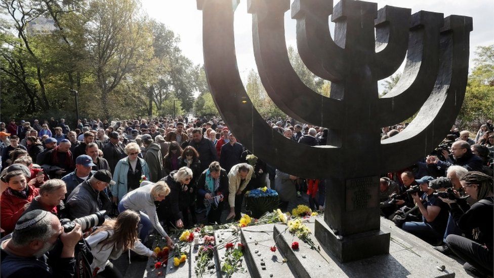 People place flowers during a ceremony at a monument commemorating the victims of Babyn Yar (Babiy Yar), one of the biggest single massacres of Jews during the Nazi Holocaust, in Kiev, Ukraine September 29, 2019.