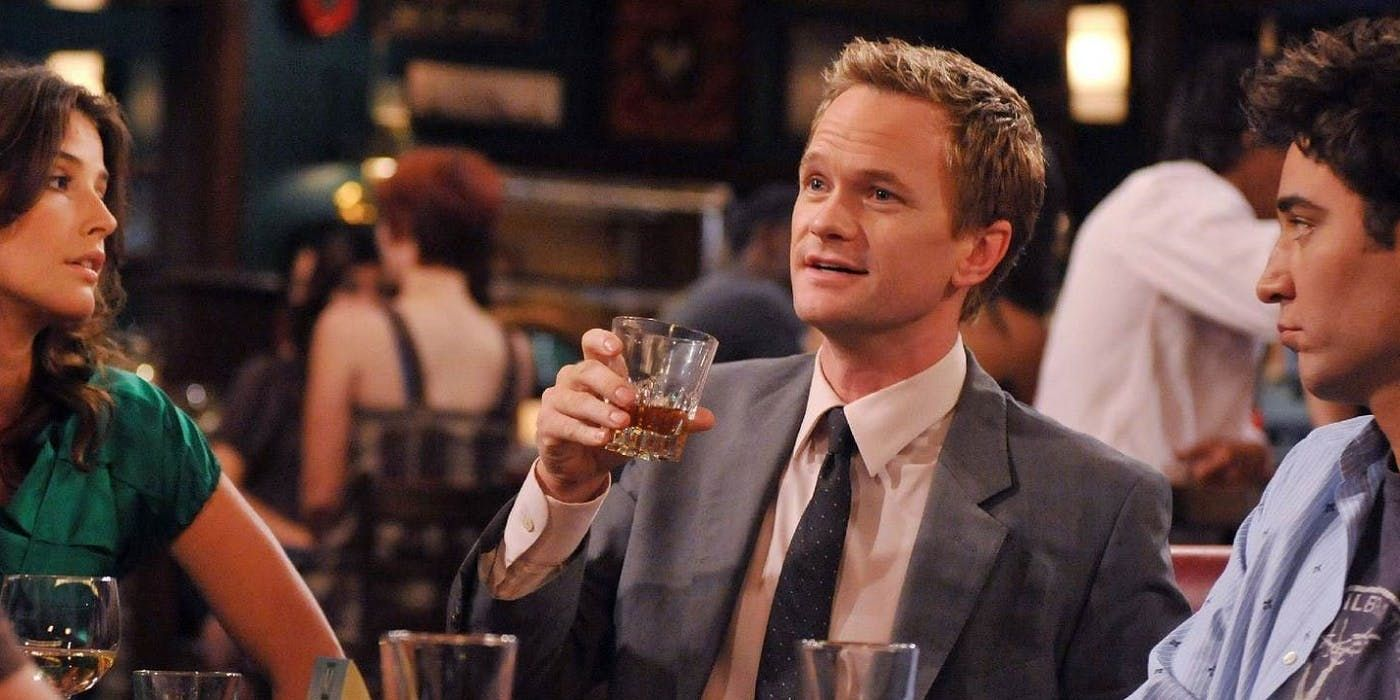 Foto com personagem Barney Stinson. de How i Met Your Mother, com copo de whisky na mão sentado na mesa com Ted Mosby e Robin Scherbatsky