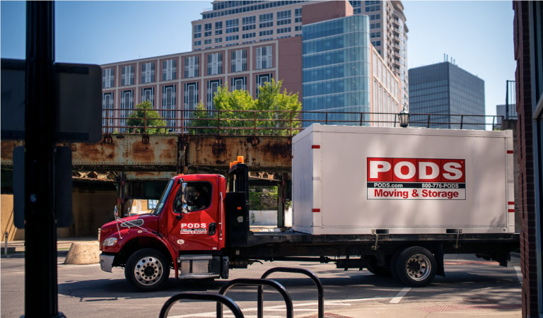 A PODS truck is transporting a PODS moving and storage container through the city of Chicago.