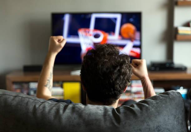 Man watching basketball on tv Man watching basketball game on tv and cheering watching basketball on tv stock pictures, royalty-free photos & images