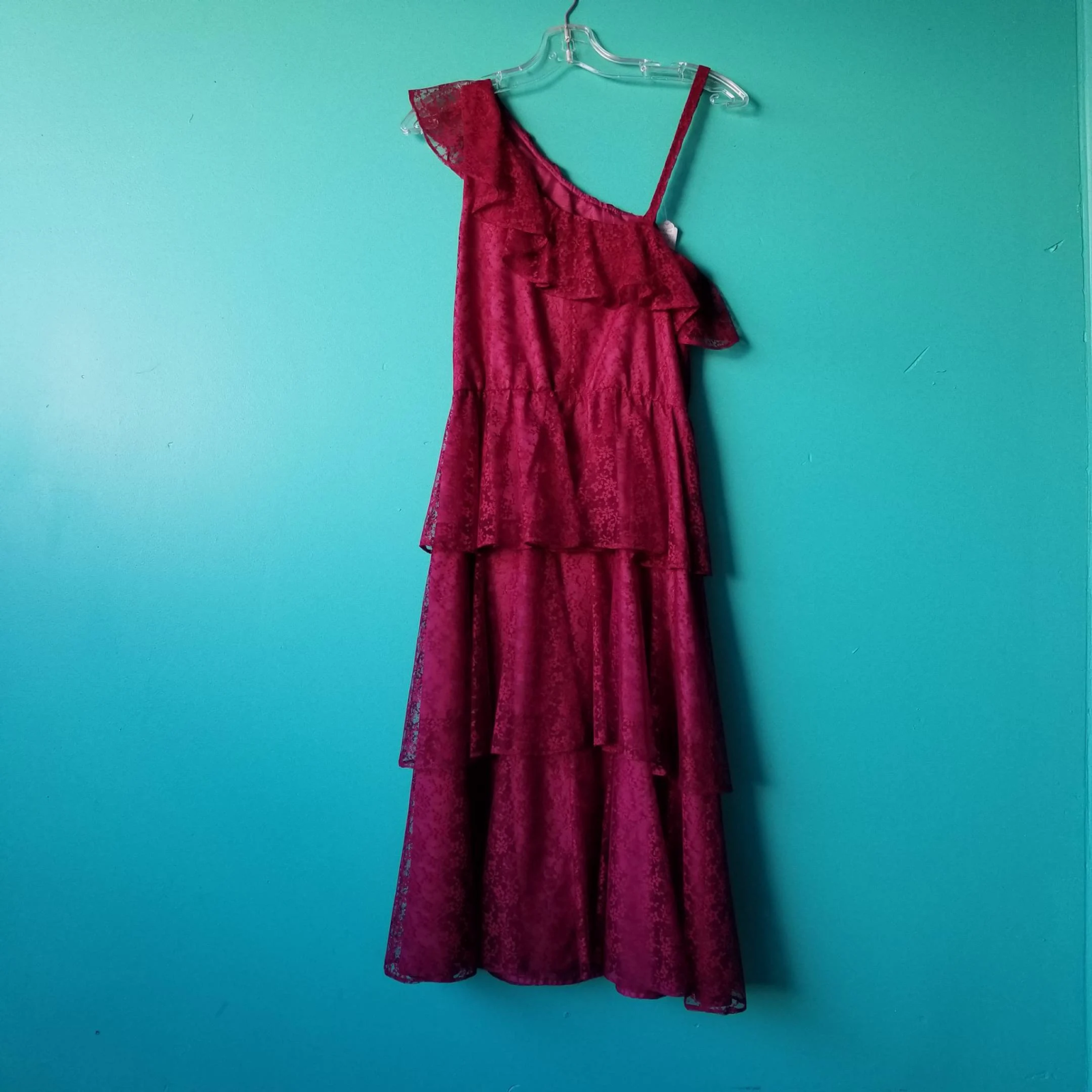 A purple dress hanging on a green background wall.