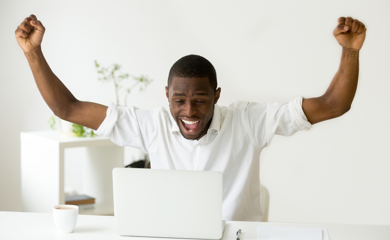 Excited man looking at laptop celebrating online win 