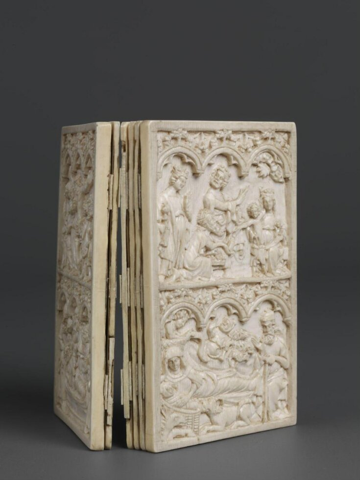 A highly decorative writing tablet made out of ivory with scenes from the Life of Christ, propped up to show the several "sheets" of wax it holds.