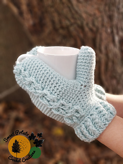 cabled crochet mittens holding a cup