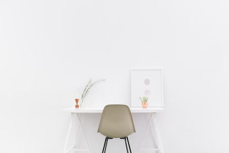 A room with a white wall, white table and a beige chair