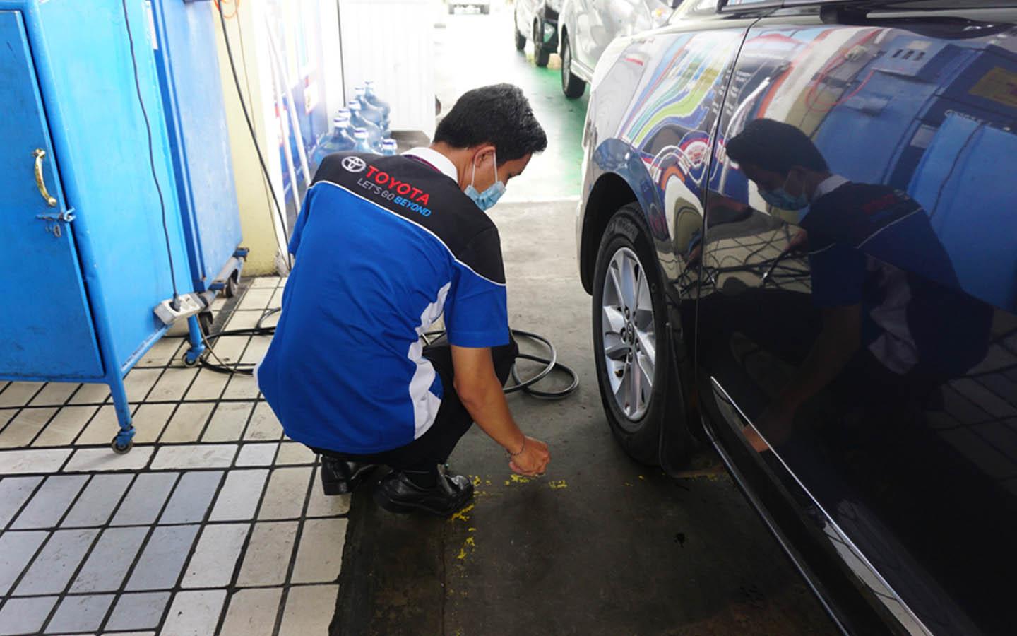 A Toyota technician checking the car’s tyre 