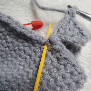 Image shows the placement of the first stitch after the second fin of the crochet shark lovey. 