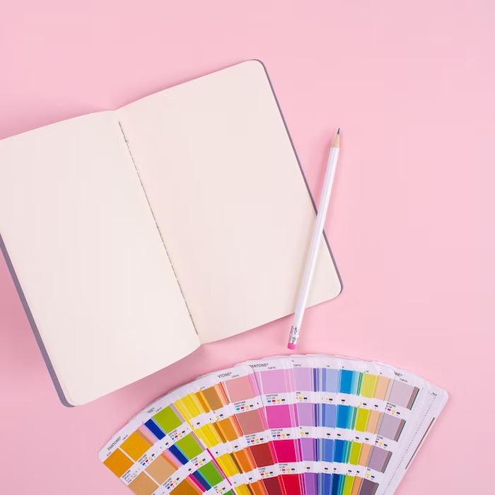 A blank notepad with a pencil lying across with color palette in front of notepad