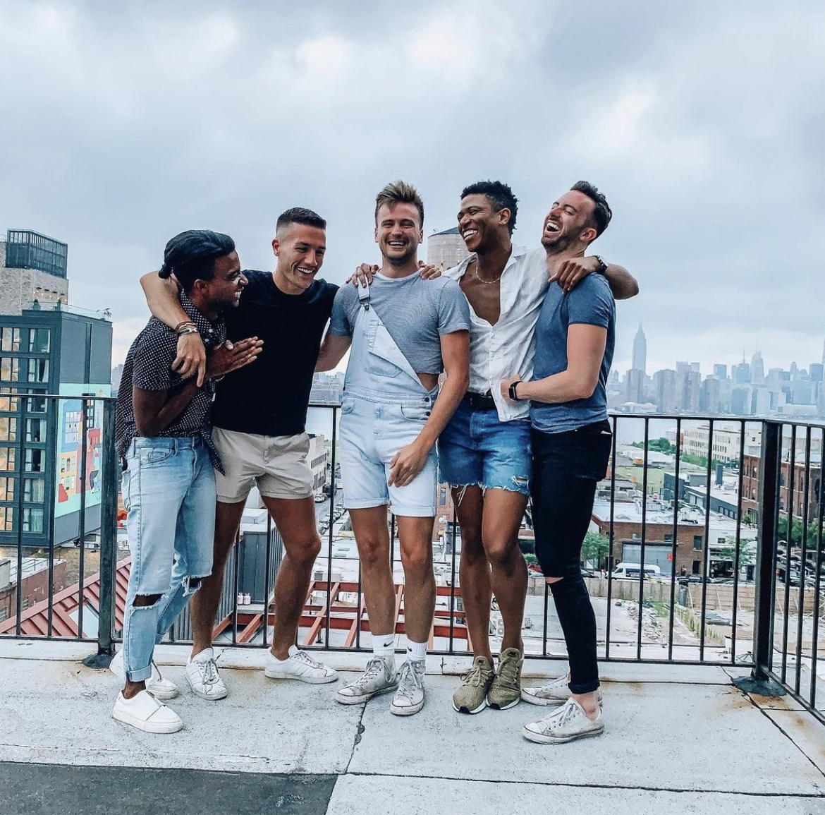 A group of guys posing in front of a city skyline.
