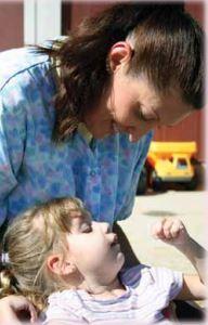 A caregiver looking down at a toddler.