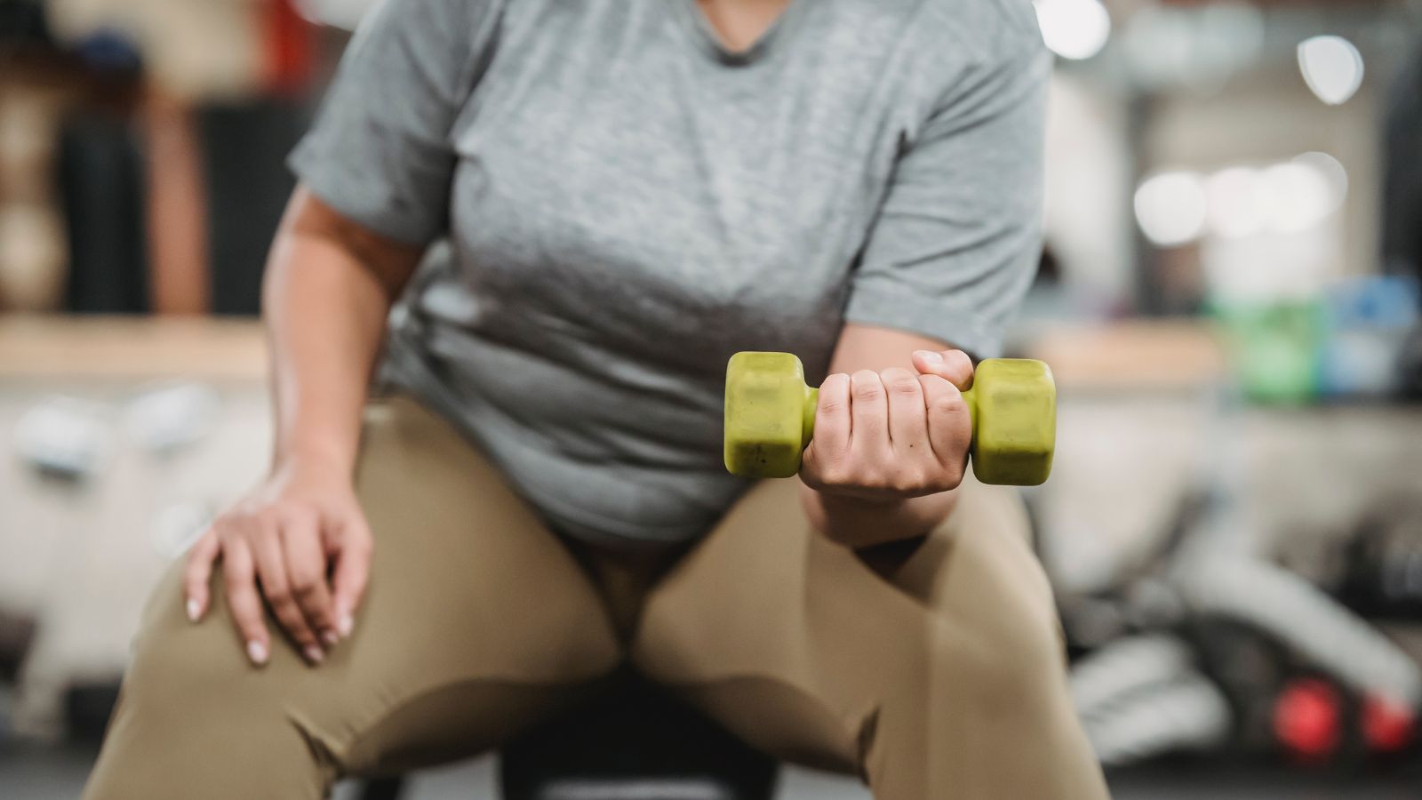 Mito sobre adelgazar. Una persona con sobrepeso haciendo pesas en el gimnasio.