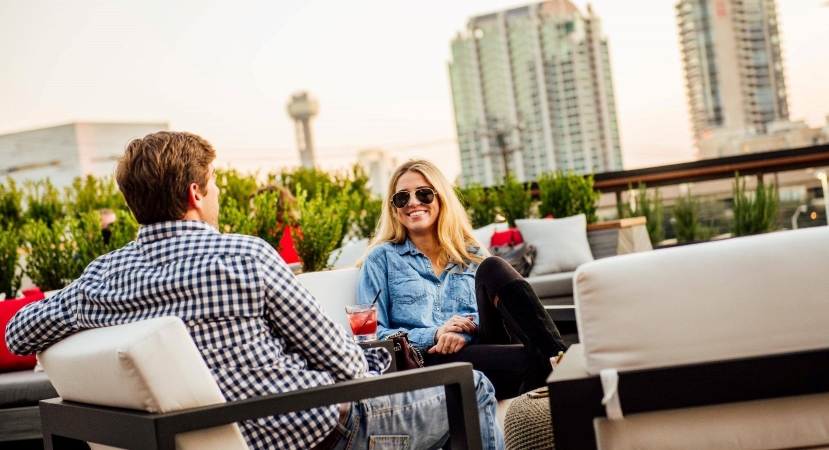 A couple dining on a rooftop in downtown Dallas. Skyscrapers can be seen in the background