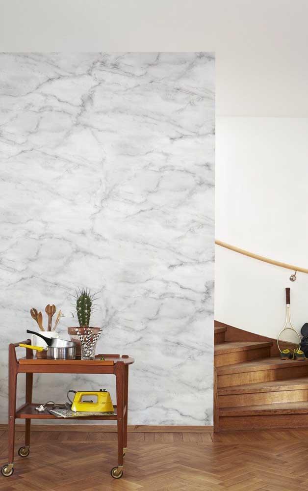Ambiente com parede de escada de marmorato claro, piso de madeira e escadeira de madeira, mesinha de madeira com acessórios.