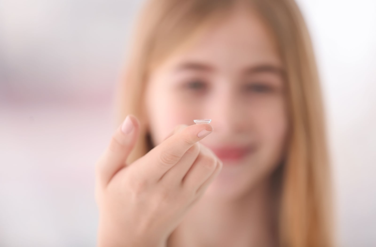  A teenage girl holding onto a contact lens on her index finger.