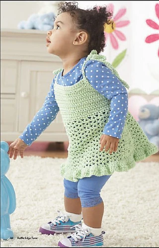toddler wearing a crocheted dres over a long sleeved shirt and leggings